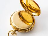 a small gold pocket watch with a key in it