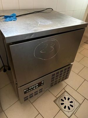 a small stainless steel refrigerator sitting on a tiled floor