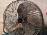 un ventilateur posé par terre près d'un mur