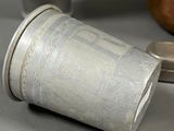 a silver cup sitting on a table next to a coin