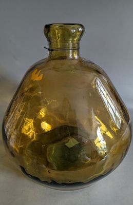 a yellow glass vase with a green apple inside of it