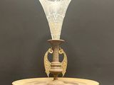 une image représentant un vase en verre posé sur un socle en bois, sur fond noir