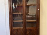 une bibliothèque ancienne en bois avec des portes vitrées dans une pièce