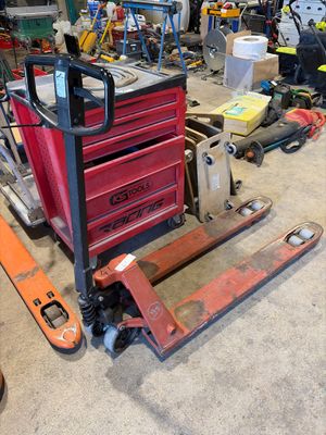un chariot élévateur dans un garage où des outils sont éparpillés sur le sol