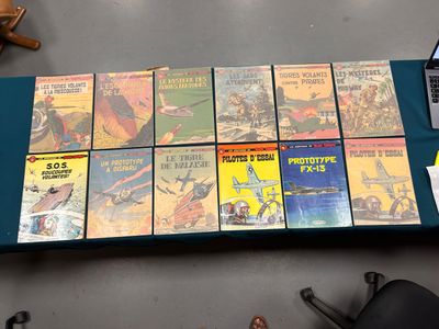 beaucoup de livres posés sur une table à côté d'un ordinateur portable