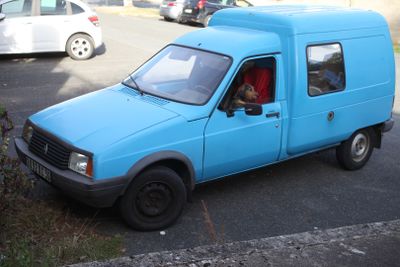 a small blue van parked on the side of the road