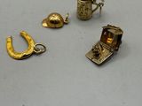 three gold charms and a silver ring on a white surface