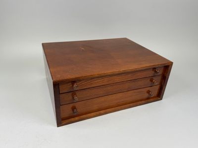 a small wooden box with three drawers on top of it