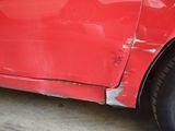 a red car that has a dent in the side of it