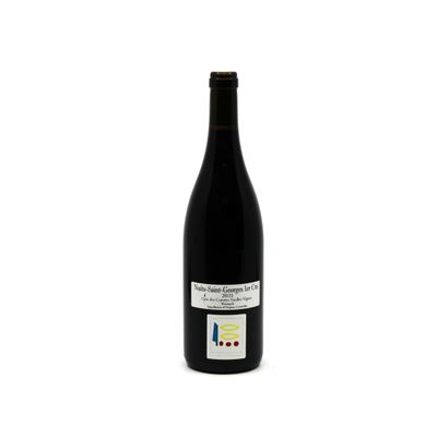 the bottle of red wine is sitting on a white surface