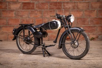 a black and white motorcycle parked in front of a brick wall