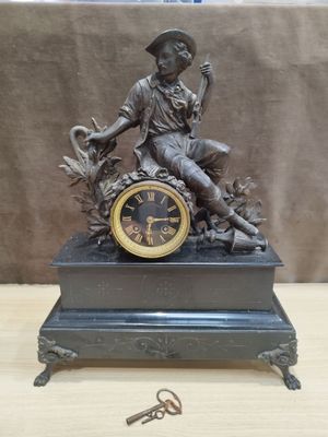 une statue représentant un homme assis sur une horloge, tenant une clé