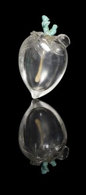 a glass apple with a figurine sitting on top of it