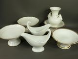 a group of white and gold china dishes and bowls