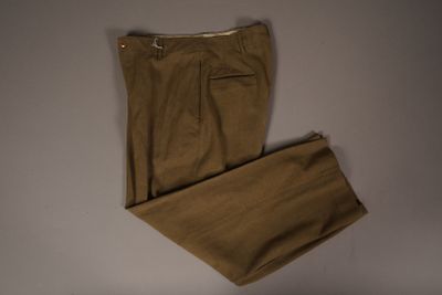 un pantalon beige posé sur une surface blanche, avec un fond blanc