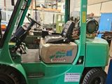 a green fork truck that is parked in a garage