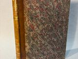 an old book sitting on top of a white cloth covered table