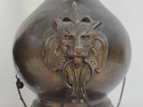 a large bronze vase with a lion head on it
