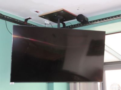 un téléviseur à écran plat suspendu au plafond dans une pièce