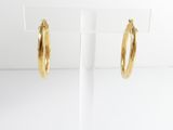 a pair of gold hoop earrings on a white stand
