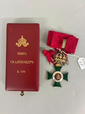 deux médailles et un livre rouge posés sur une table blanche