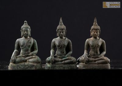three statues of buddhas sitting on top of a black surface