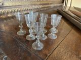 plusieurs verres à vin vides posés sur une table en bois devant un miroir