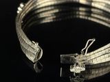 a close up of a silver bracelet on a black surface