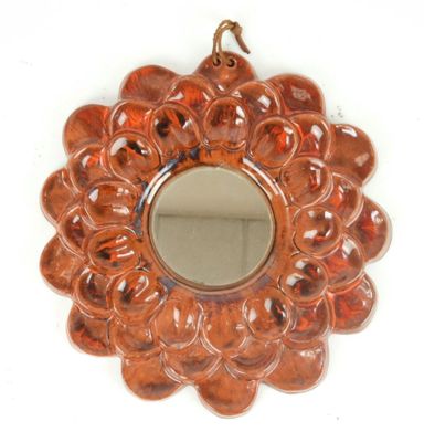 an orange flower shaped mirror hanging on a white wall