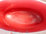 a red bowl sitting on a table with a spoon in it