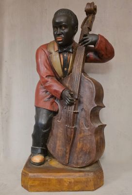 statue représentant un homme jouant du violoncelle et de la contrebasse, posée sur un socle en bois