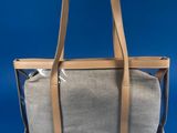 grey canvas and leather tote bag on blue background