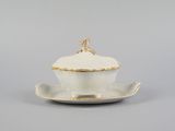 an image of a white and gold covered dish on a saucer
