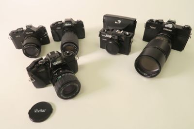 several cameras are lined up on a white surface with a lens cap