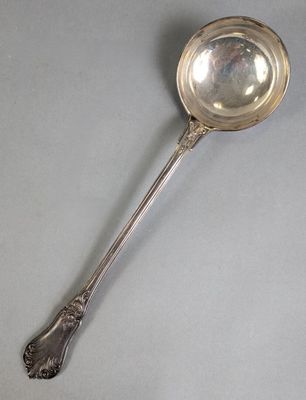 an antique silver spoon with a spoon handle on a gray surface