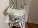 une chaise haute blanche pour bébé, dans un coin de la pièce