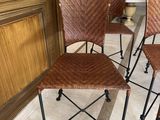 four chairs with woven seats sit in a row on a marble floor
