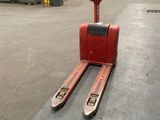 a forklift in a warehouse with lots of pallets in the background
