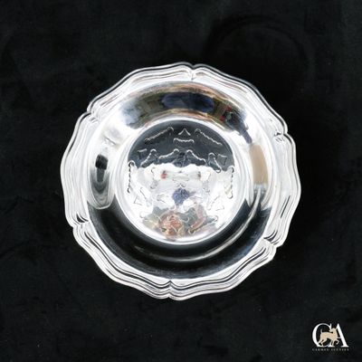 une assiette ancienne en argent sur fond noir, avec une cuillère en argent au centre
