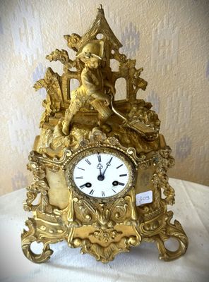 une horloge en or posée sur une table recouverte d'une nappe blanche