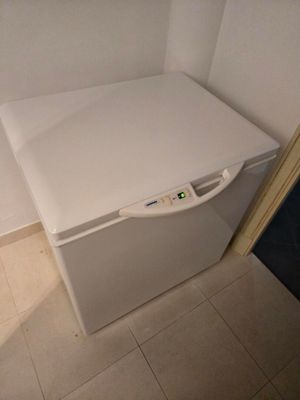 un petit réfrigérateur blanc dans le coin d'une pièce