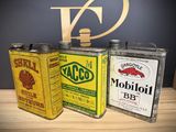 three old oil cans sitting on top of a table next to each other