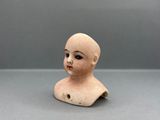 a small clay head of a doll on a table