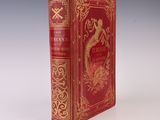 un vieux livre à la couverture rouge posé sur une table blanche