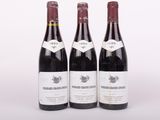 trois bouteilles de vin rouge posées l'une à côté de l'autre sur une surface blanche