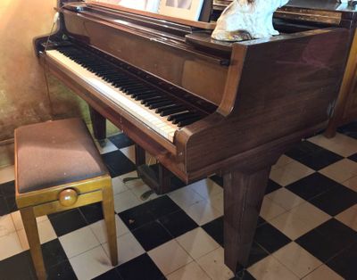 un piano dans un coin de la pièce, avec un tableau posé dessus