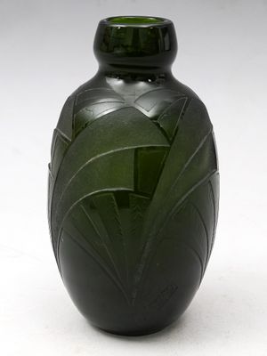 un vase vert posé sur une surface blanche