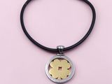 un pendentif en forme de fleur, en argent et en or, monté sur un cordon noir