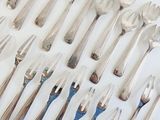 many spoons and forks laid out on a table