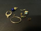 several rings and earrings on a table with a black background